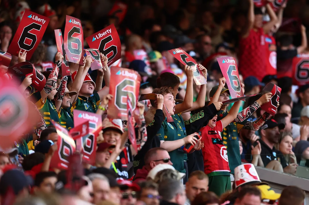Young cricket fans holding up six signs at a Big Bash match in Australia